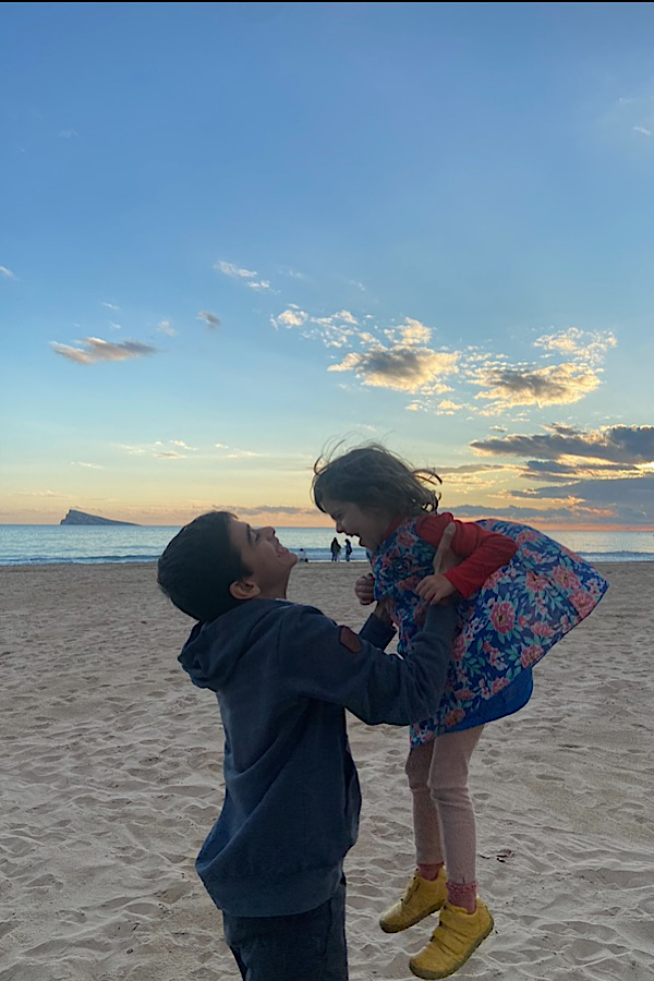 Bruder und Schwester am Strand lachend