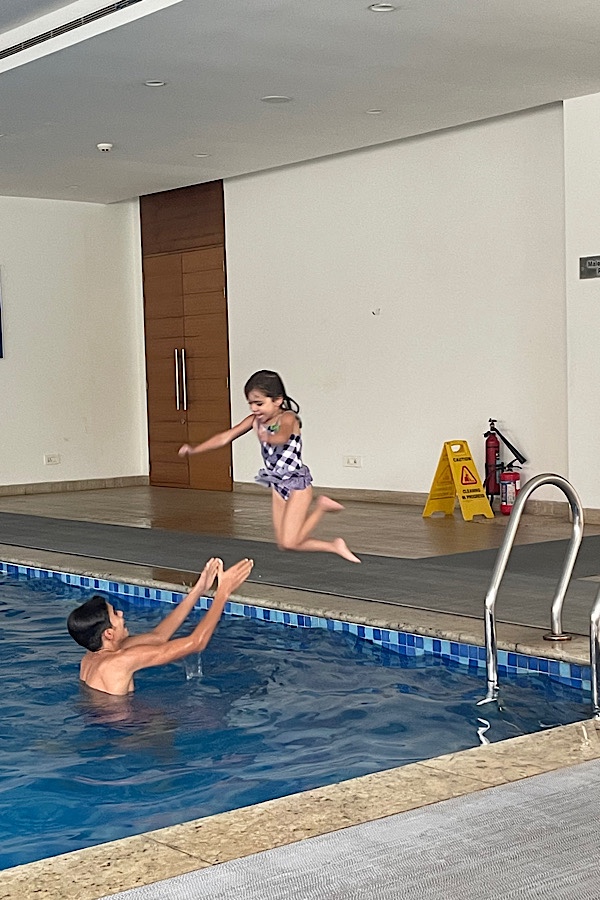 Kind springt in die Arme eines Jungen im Schwimmbad